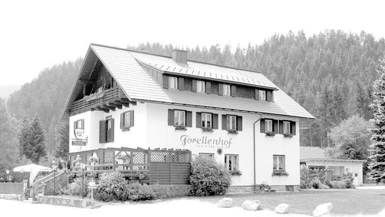 Tradičný hostinec s nápisom "Forellenhof Schiefer" na pozadí lesa.