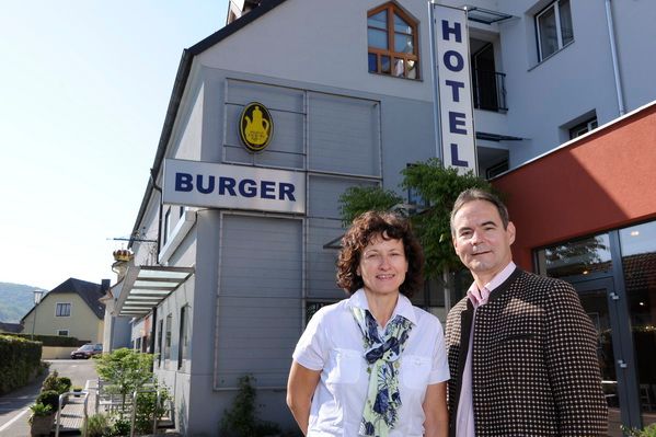 Muž a žena stoja pred budovou s nápisom "Hotel Burger".