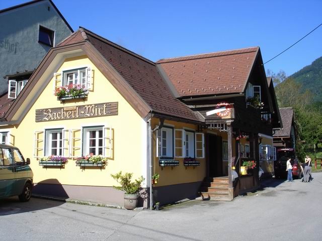 Tradičný hostinec so žltou fasádou a kvetinovými truhlíky pod oknami.