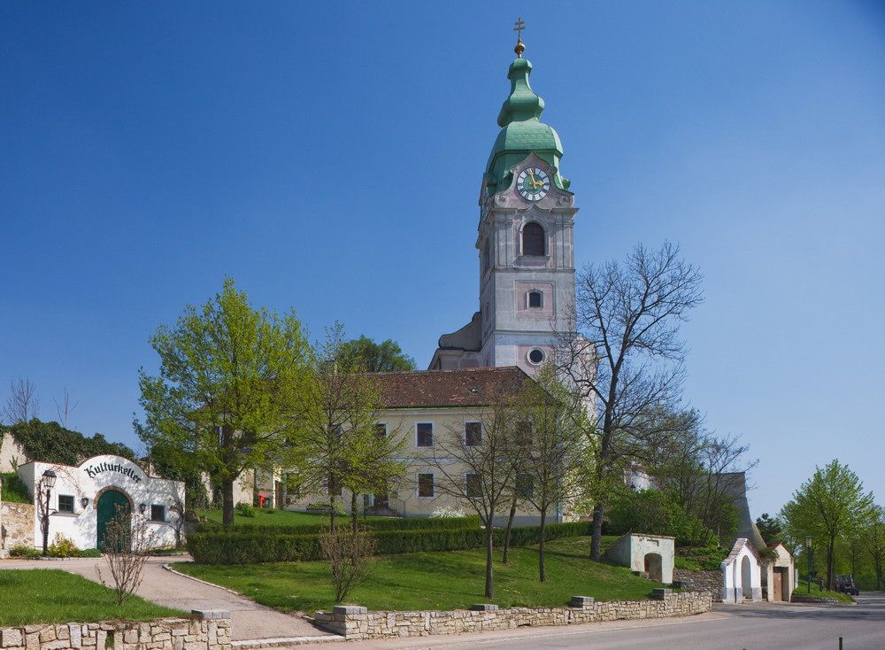 Kostol v Unterretzbachu so zelenou vežou a okolitými budovami.