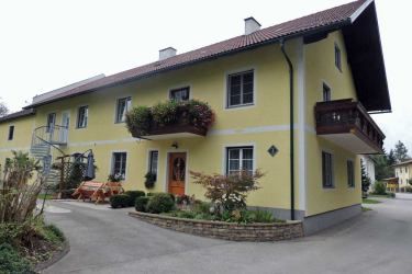 Žltý dvojpodlažný dom s balkónom a záhradou.