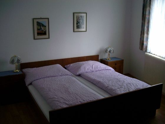 Jedna spálňa s manželskou posteľou, dvoma nočnými stolíkmi a dvoma stolnými lampami.