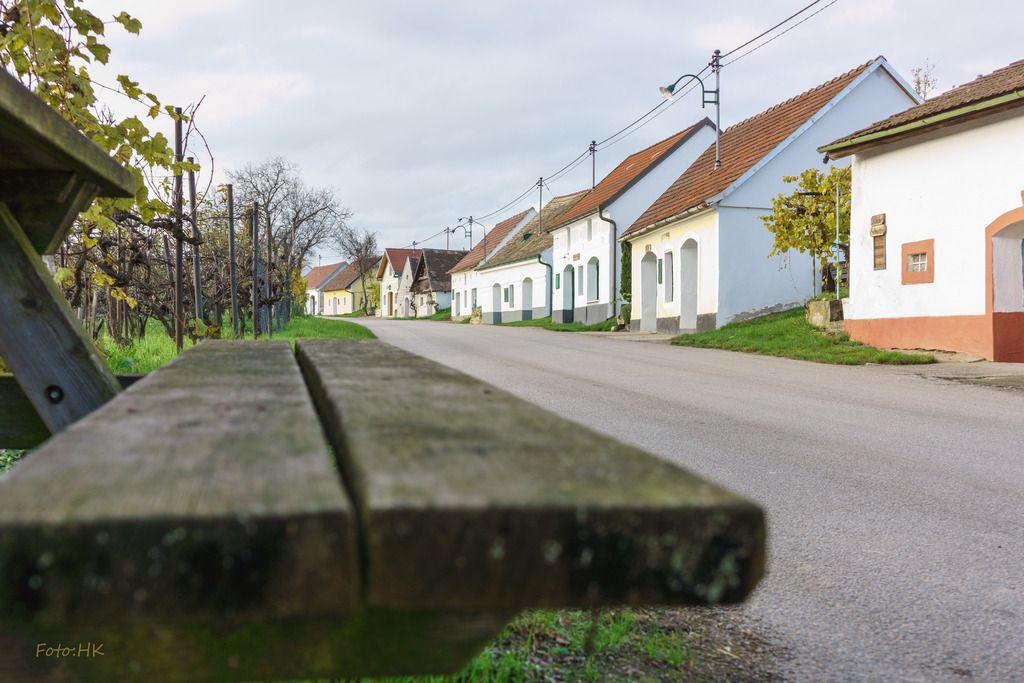 Vínne uličky v obci Niederschleinz s vínnymi pivnicami a lavičkou v popredí.
