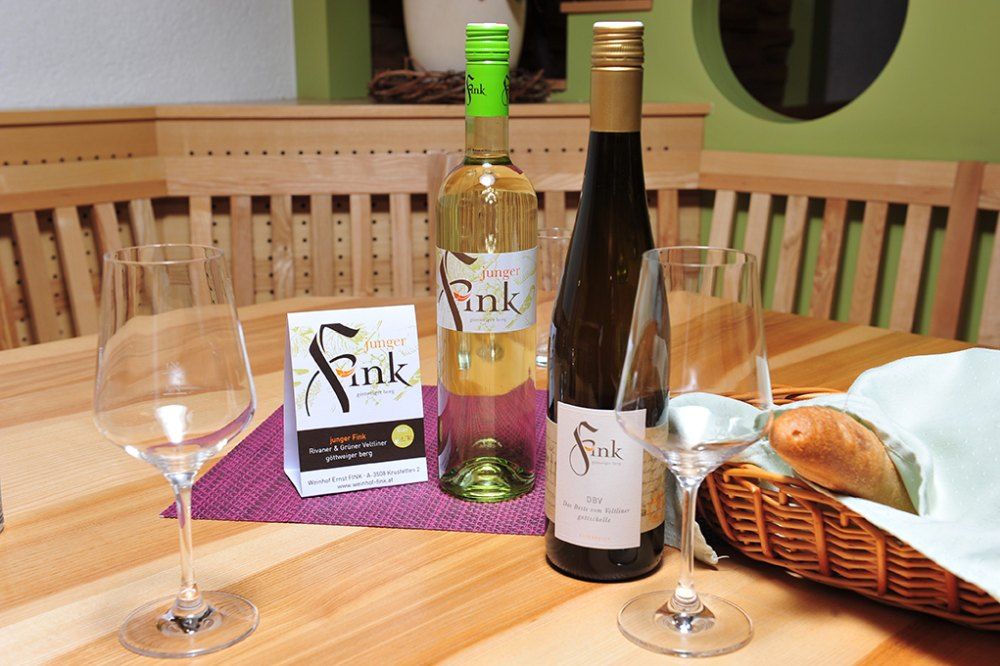 Dve fľaše vína a poháre na drevenom stole s košíkom na chlieb.