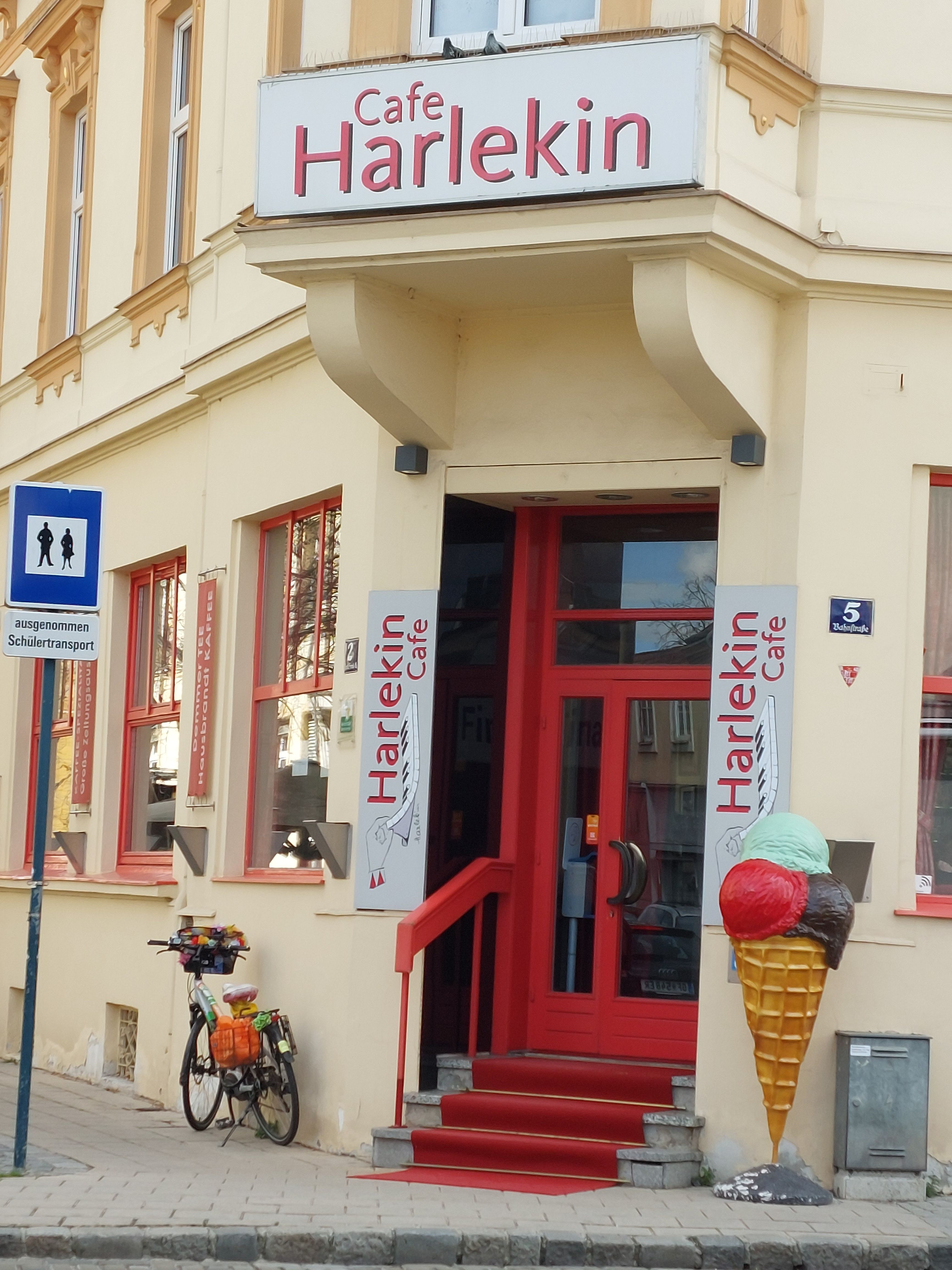 Vchod do kaviarne Harlekin s červenými dverami a dekoráciou zmrzlinových kornútov.