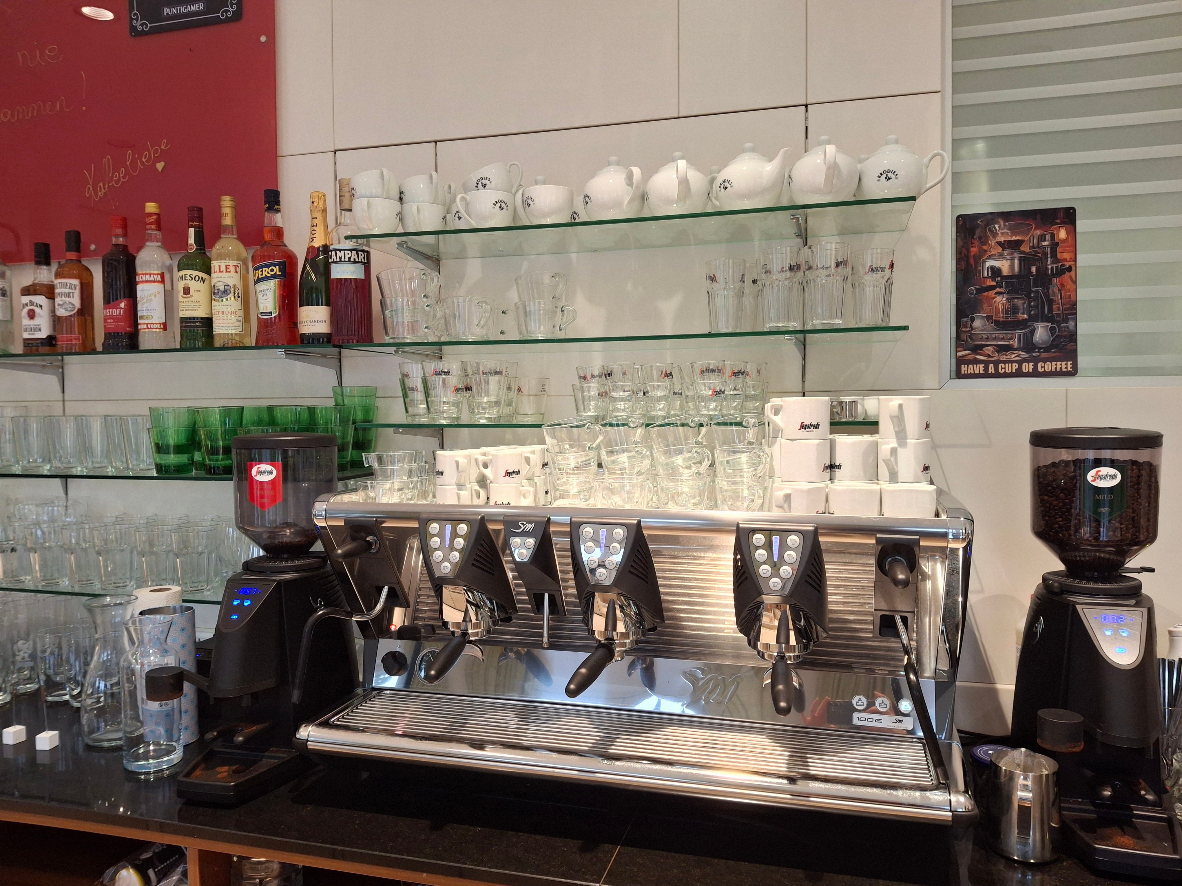 Kávovar so šálkami a pohármi v kaviarni.