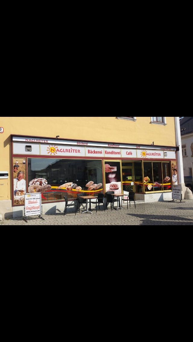 Exteriérový pohľad na kaviareň Café-Bäckerei Naglreiter so stolmi a stoličkami pred obchodom.