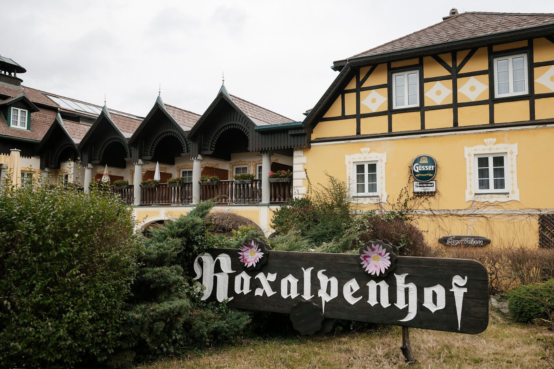 Tradičný hostinec so žltou fasádou a drevenými verandami, pred ktorým je nápis "Raxalpenhof".