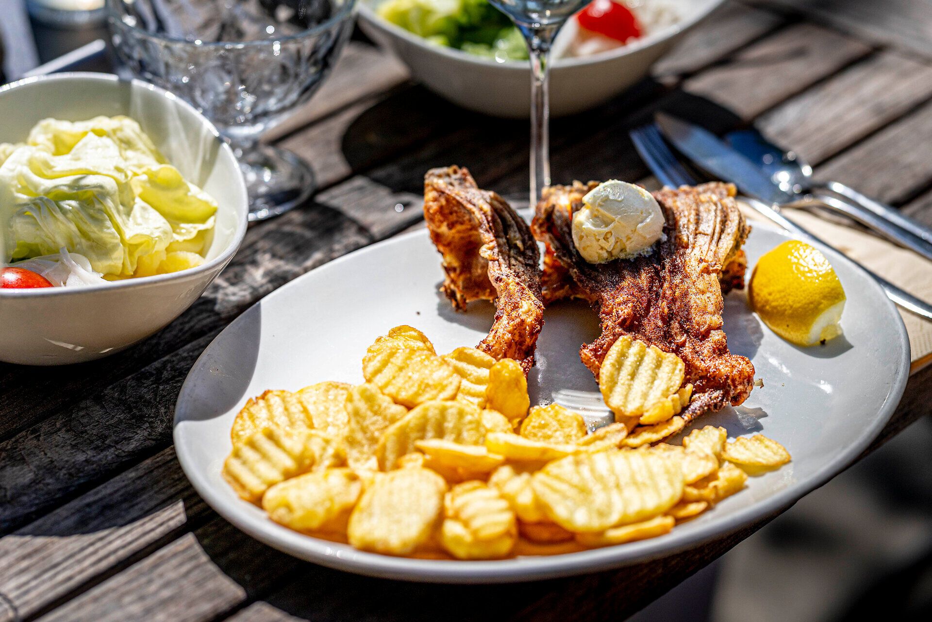Rybie jedlo a plátky zemiakov na bielom tanieri. 