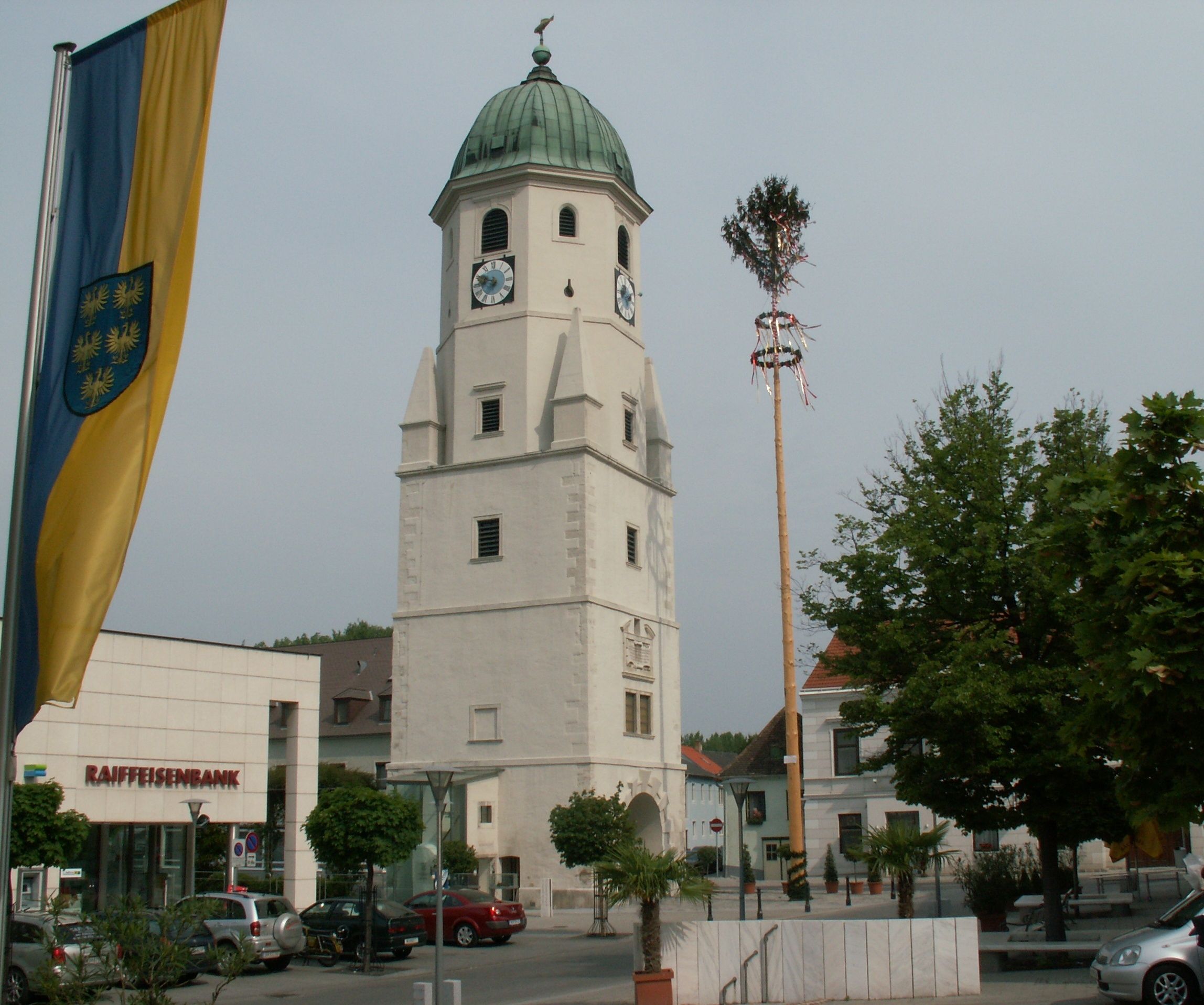 Mestská veža vo Fischamende s májom a vlajkou v popredí.