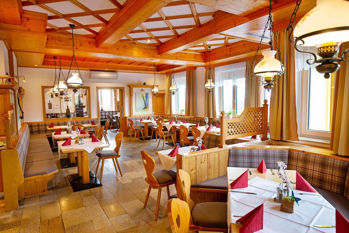 Útulná reštaurácia s dreveným nábytkom a prestretými stolmi.