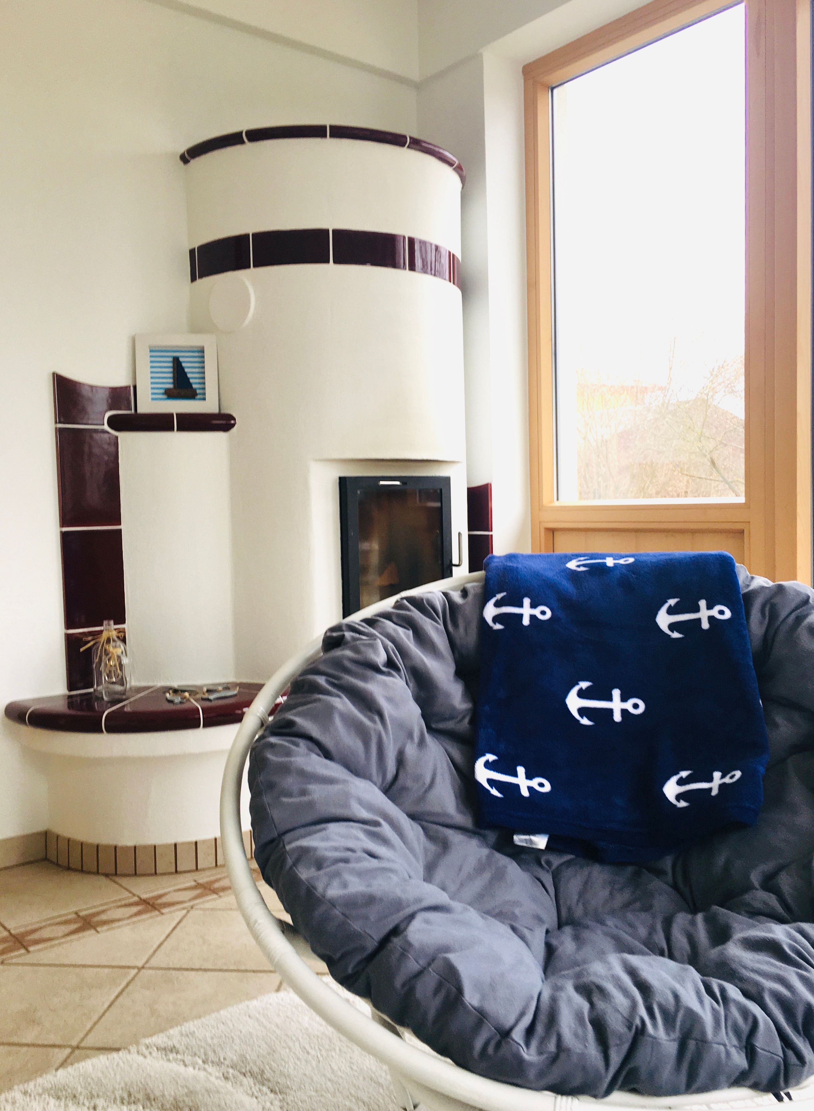 Útulná obývacia izba s kachľovou pecou a kreslom.