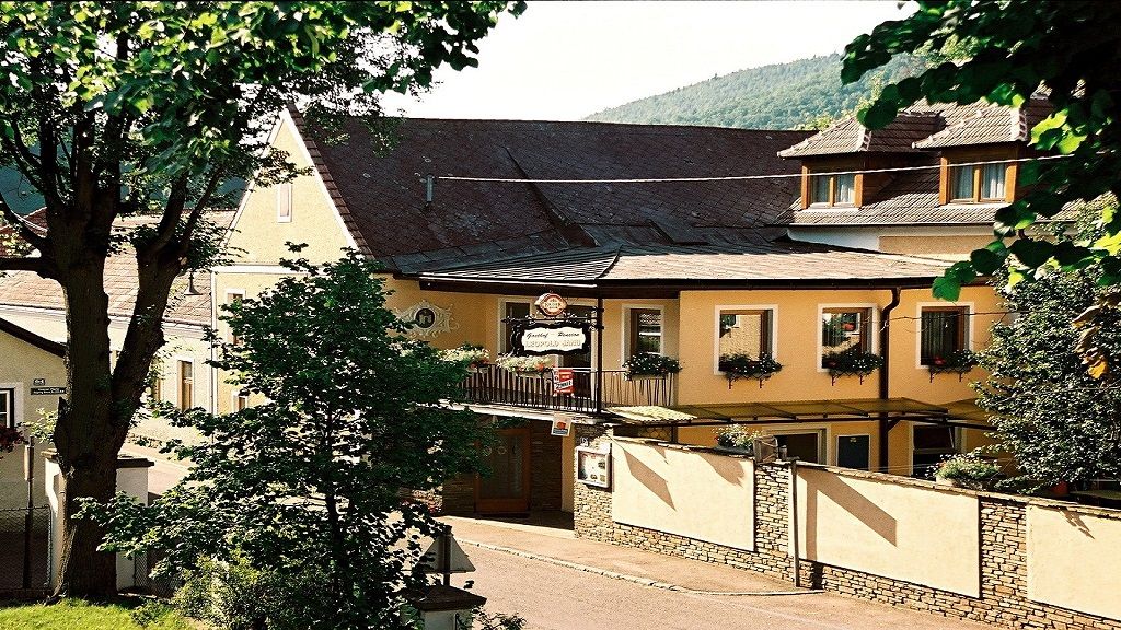 Exteriérový pohľad na penzión Leopold Janu so žltou fasádou a kvetinovými truhlíky.