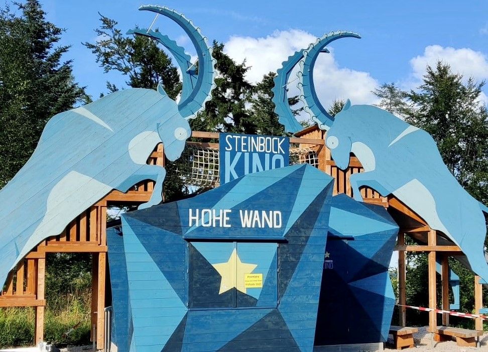 Vstup do kina Steinbock v prírodnom parku Hohe Wand so siluetami modrých kozorožcov.