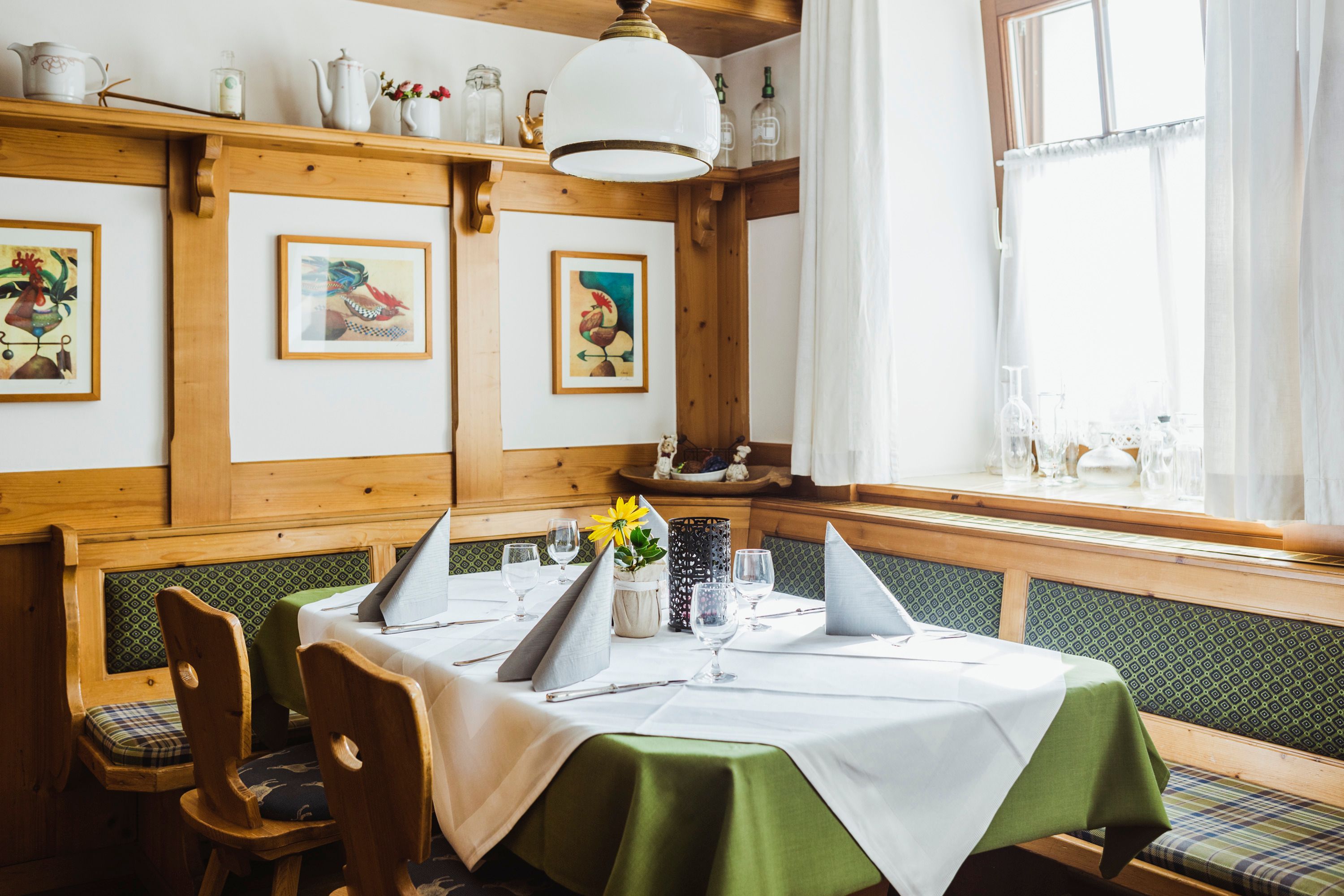 Útulný salónik s dreveným nábytkom, prestretým stolom a obrazmi na stene.