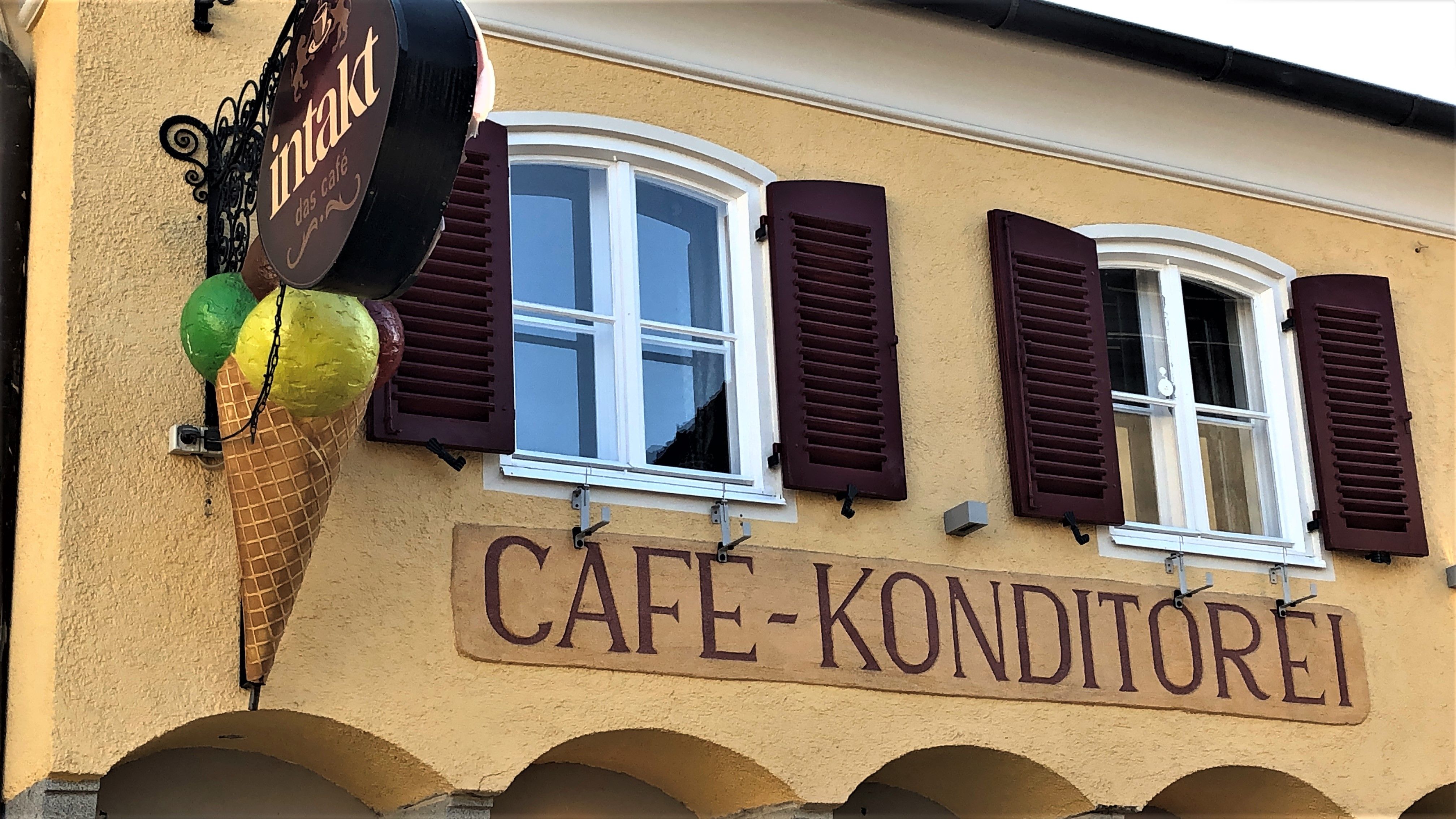 Fasáda kaviarne s dekoráciou zmrzlinových kornútov a nápisom "Cafe-Konditorei".