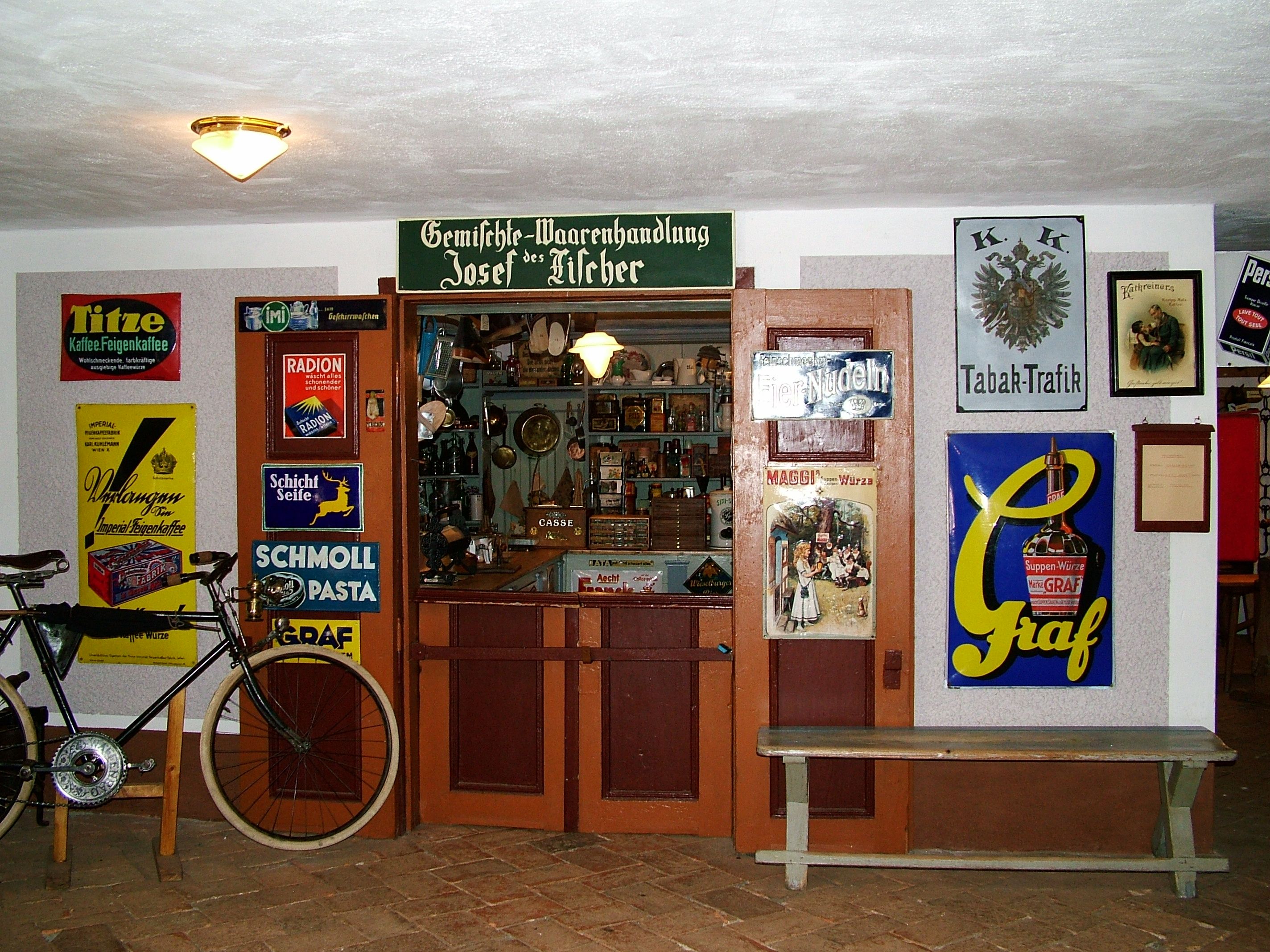 Historický obchod vo farmárskom múzeu Mostviertel so starými reklamnými nápismi a bicyklom.
