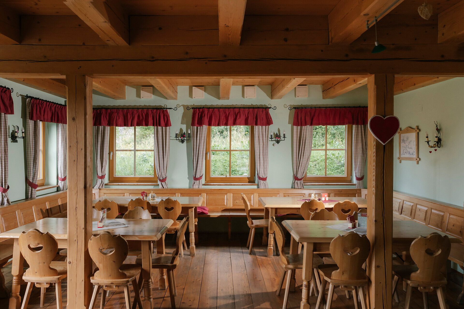 Jedáleň s drevenými stolmi a závesmi v horskej chate Hengsthütte na Schneebergu