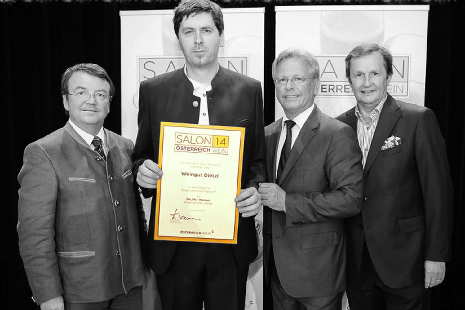Štyria muži v oblekoch držia pred kamerou Ocenenia s nápisom "Salon 14 Austria Wine".