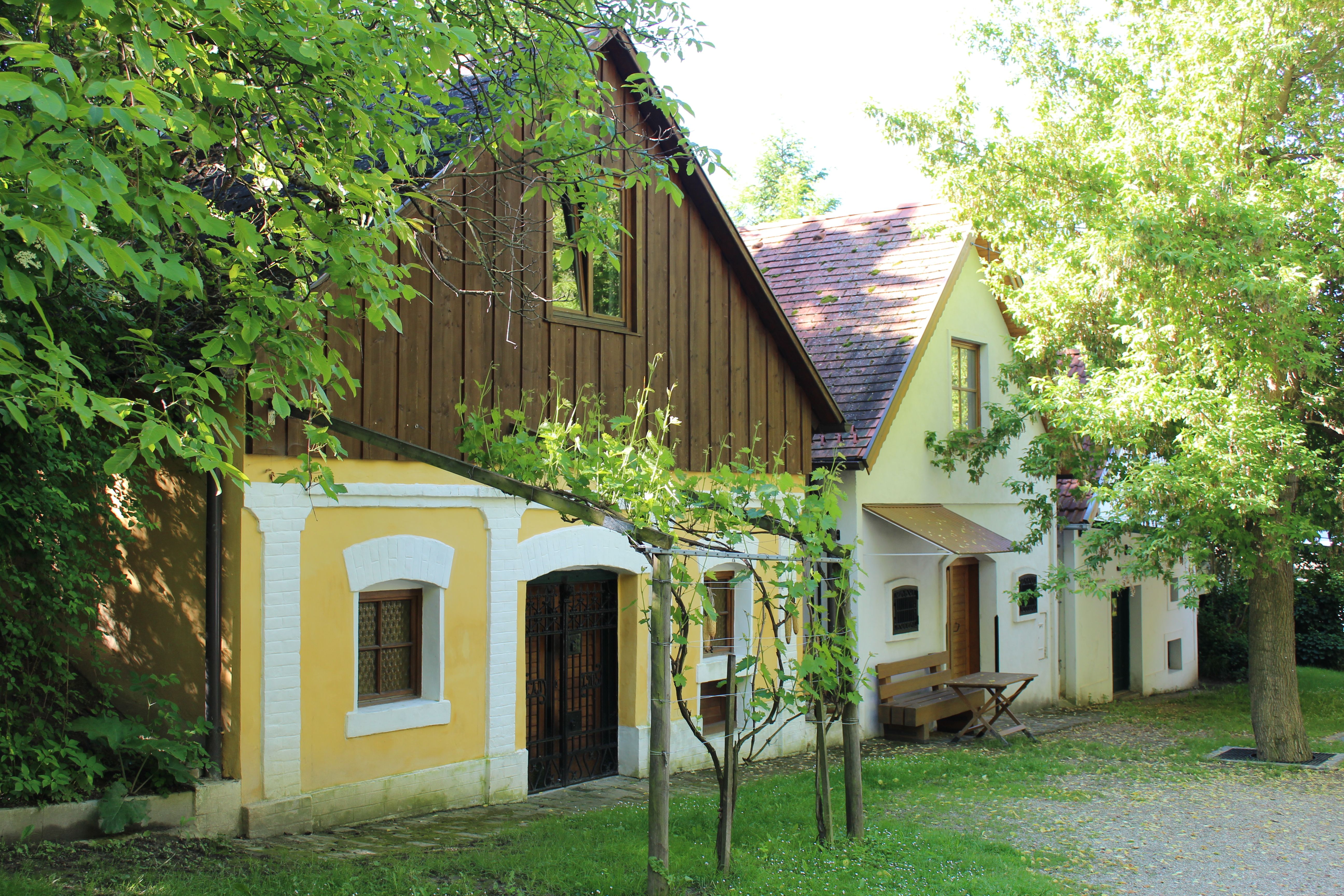 Tradičné vínne pivnice v Vínnych uličkách vo Wolkersdorfe, obklopené zelenými stromami a viničom.
