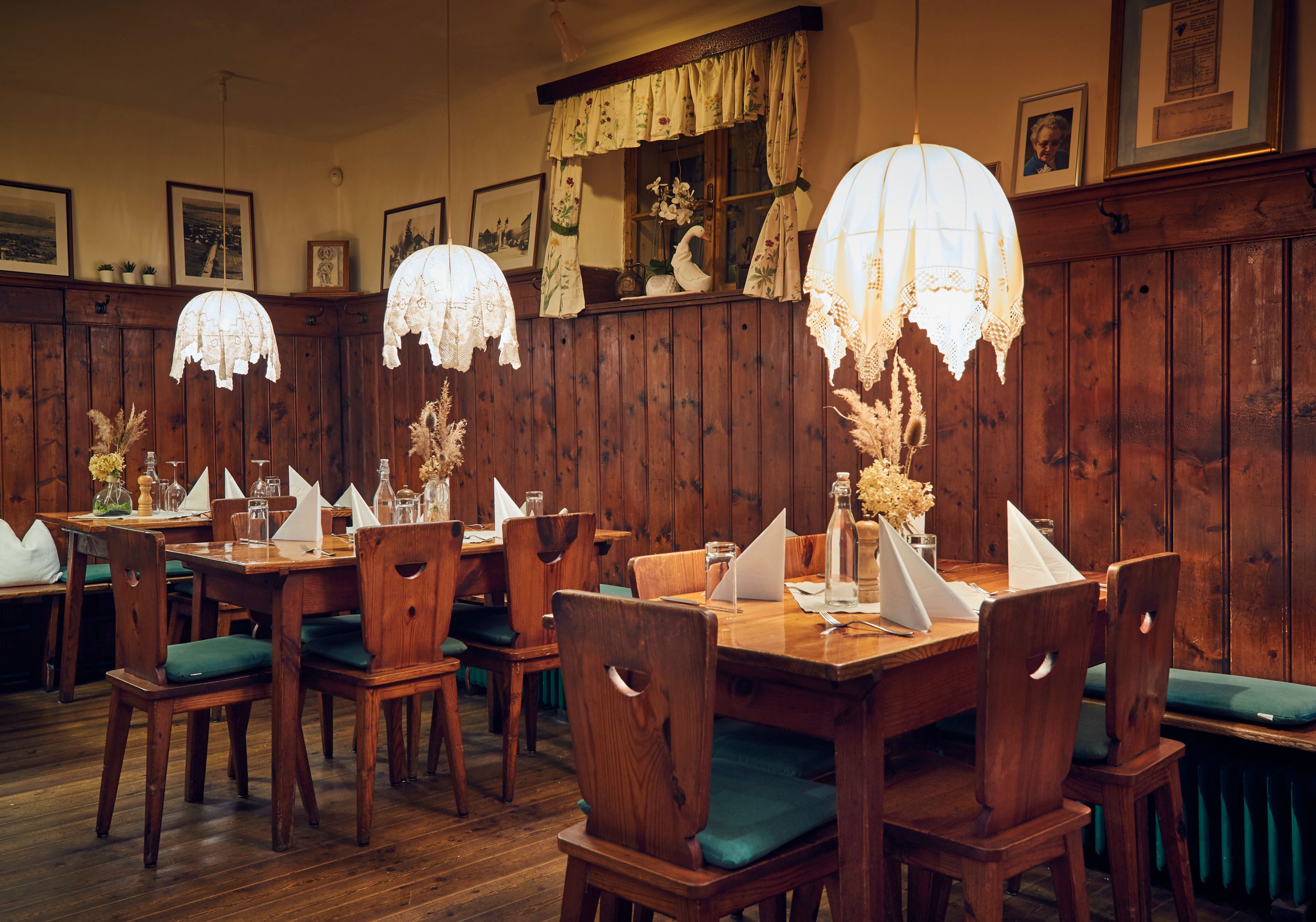 Útulný salónik s dreveným nábytkom, dekoráciami na stole a závesnými lampami.