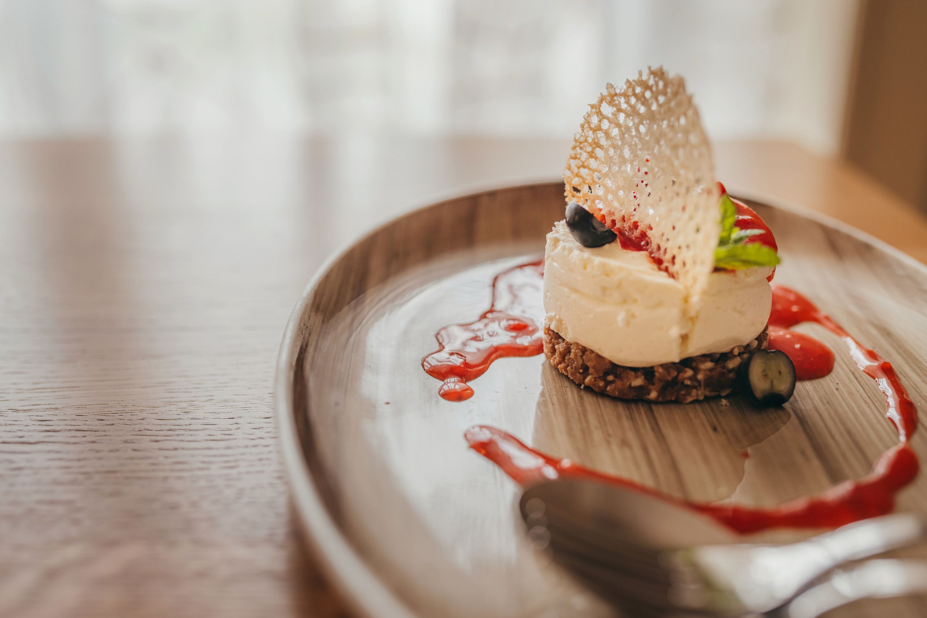 Mini tvarohový koláč s jahodovým coulis podávaný na tanieri.