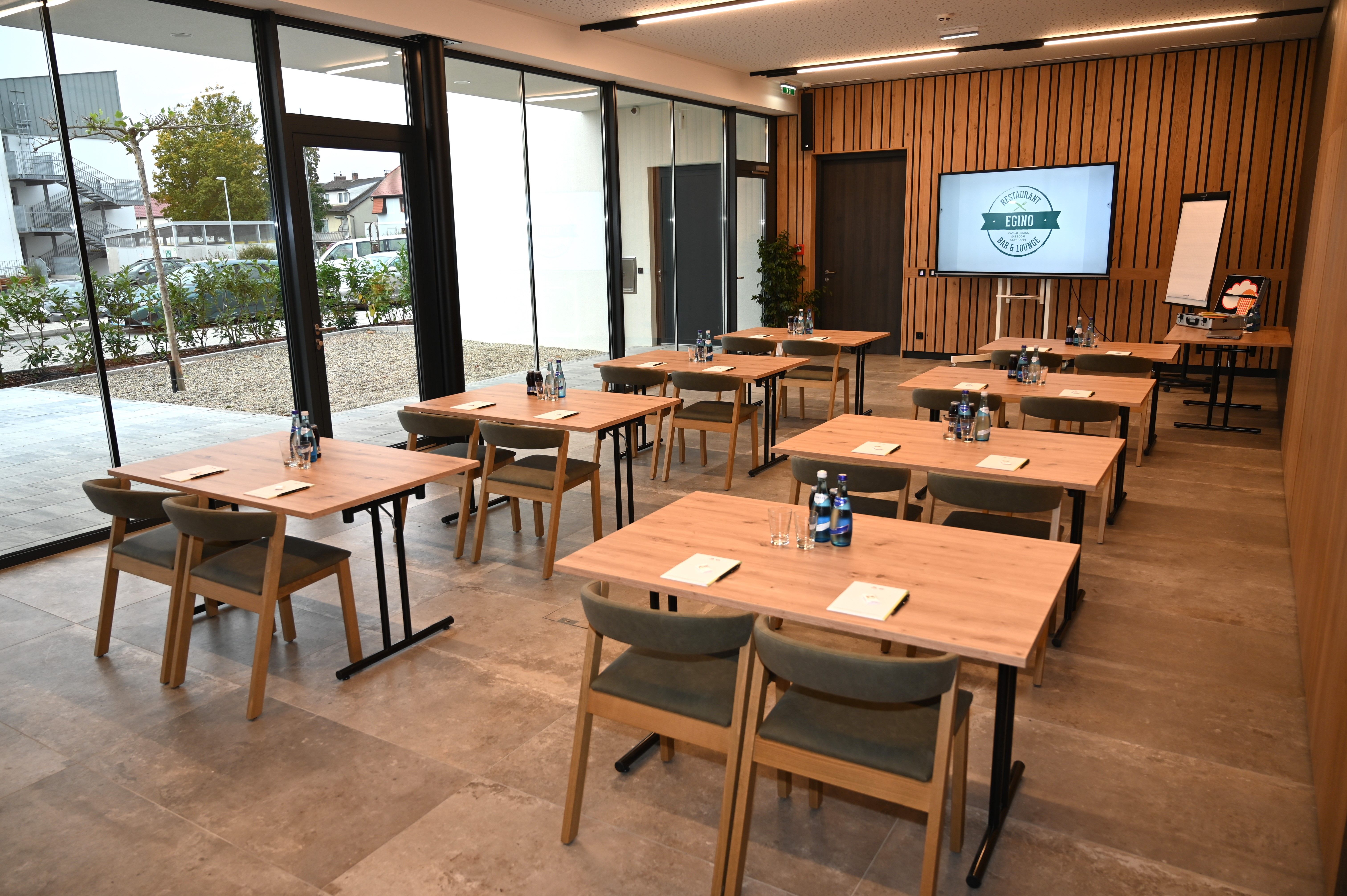 Moderná seminárna miestnosť s drevenými stolmi, stoličkami a prezentačnou technikou.