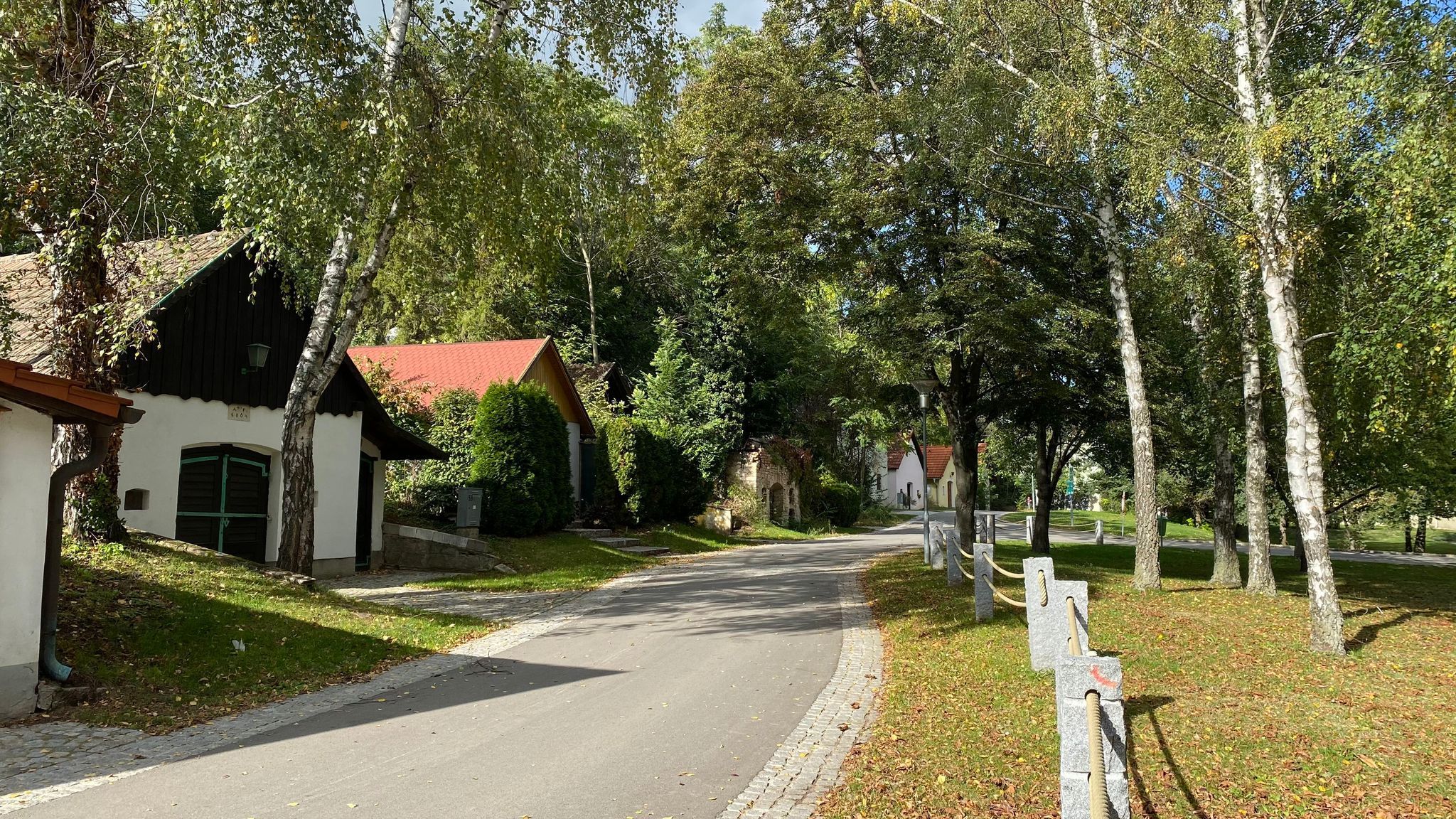 Malebná ulica (rad pivníc) s malými domčekmi a stromami vo vidieckom prostredí.