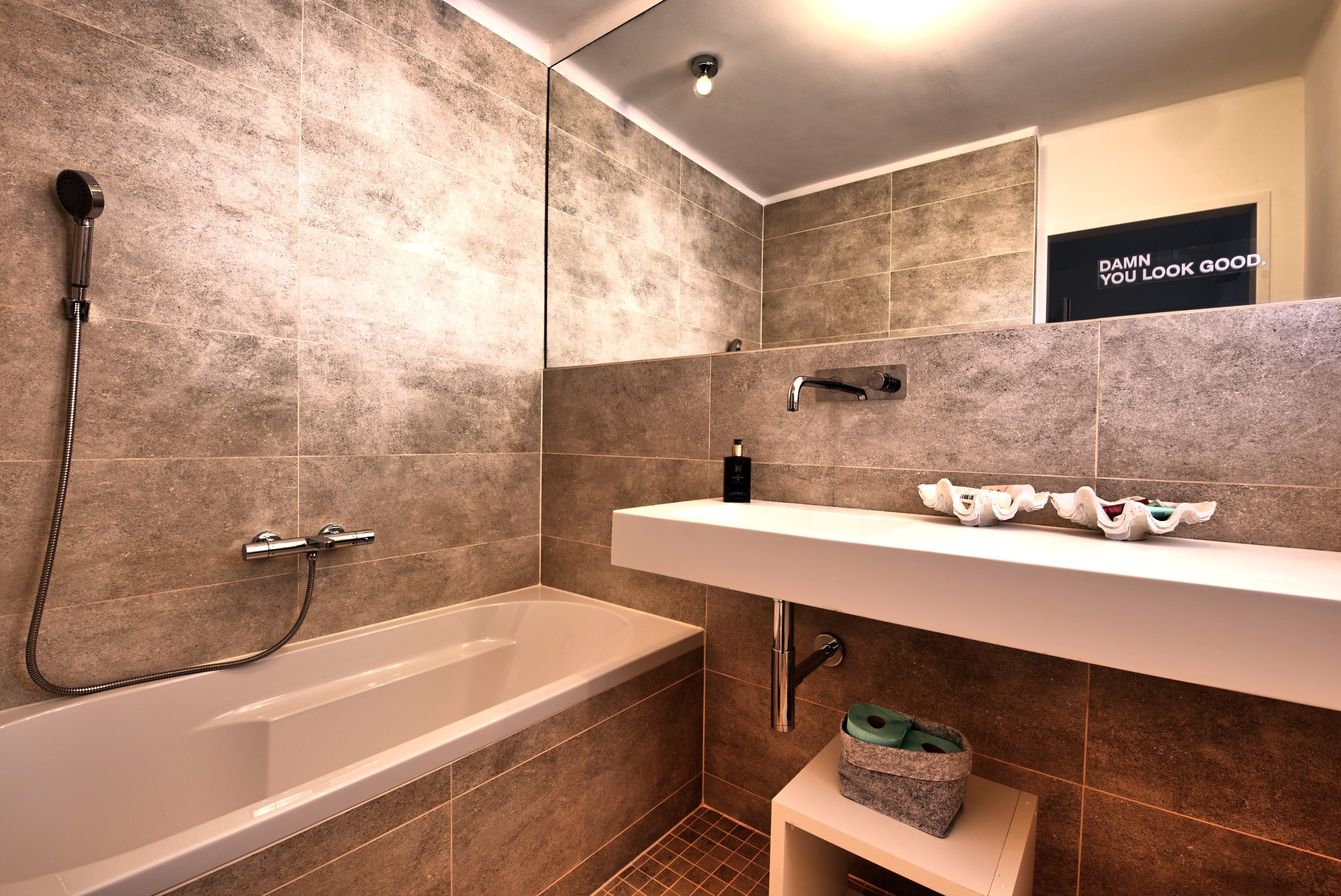 Moderná kúpeľňa s vaňou, umývadlom a veľkým zrkadlom.