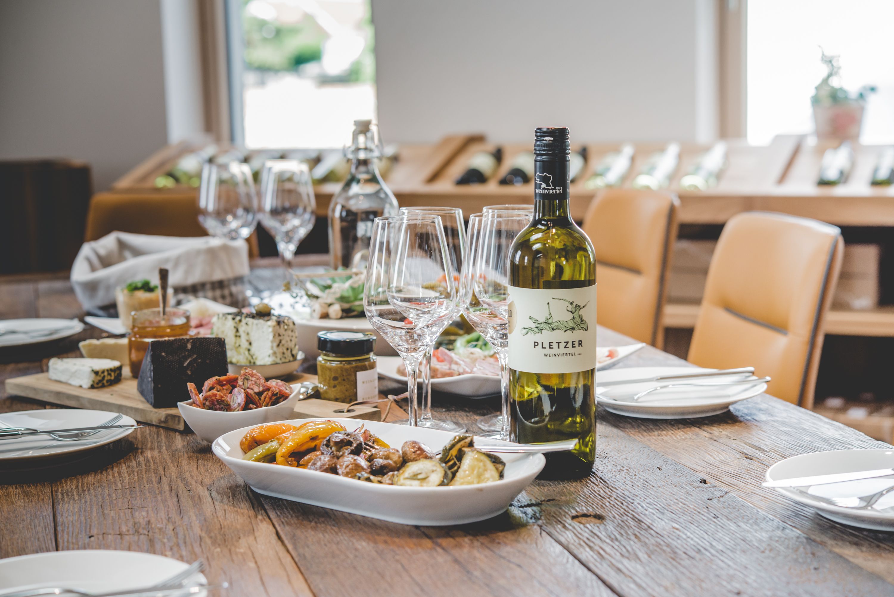 Položený stôl s fľašou vína, pohármi a rôznym riadom.