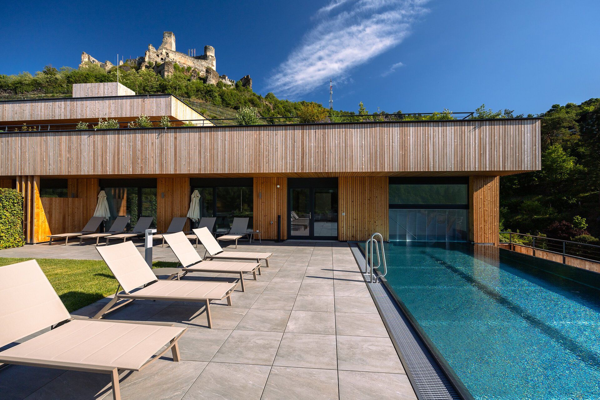 Einladende Liegen säumen den glitzernden Pool, während die sanften Hügel im Hintergrund eine malerische Kulisse bieten. Hier, umgeben von Weinreben und der frischen Luft, lässt sich der Sommer in vollen Zügen genießen.