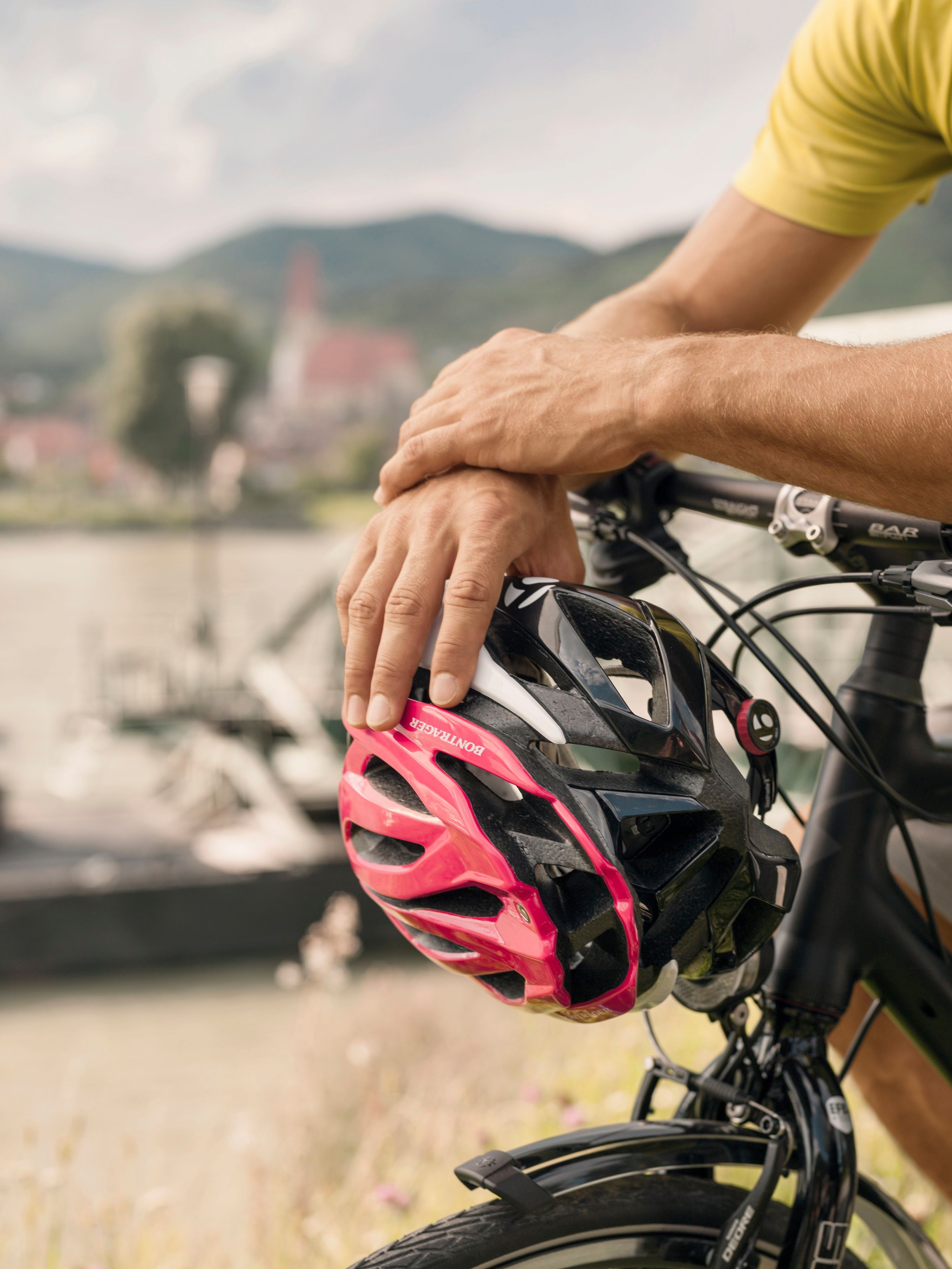Dve ruky držiace cyklistickú prilbu na riadidlách bicykla