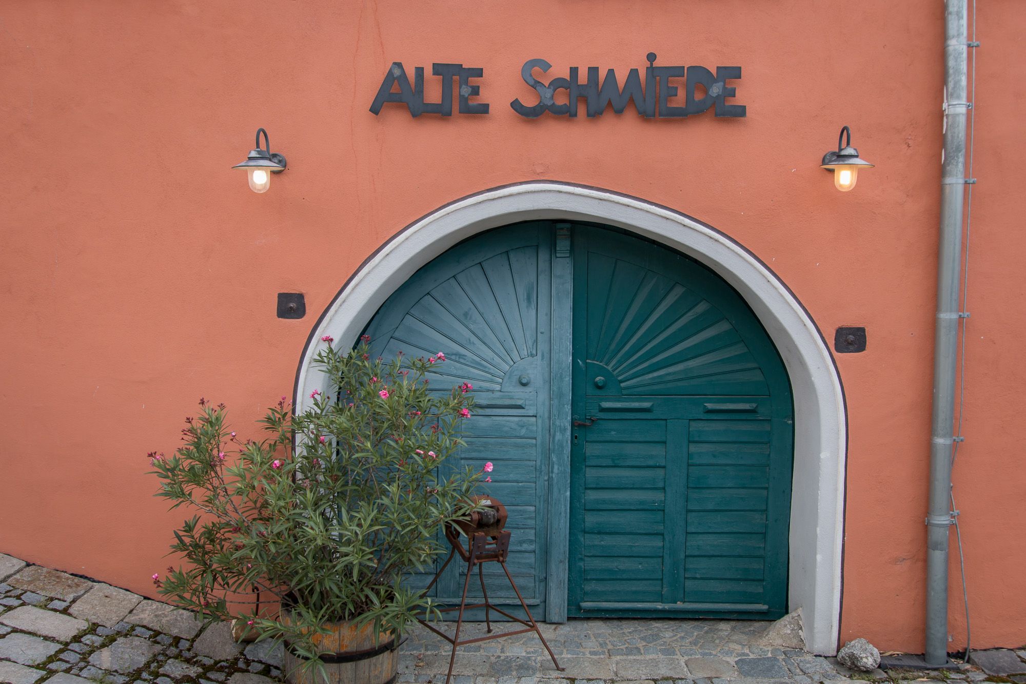 Stará brána s nápisom "Alte Schmiede" a rastlinami pred ňou.