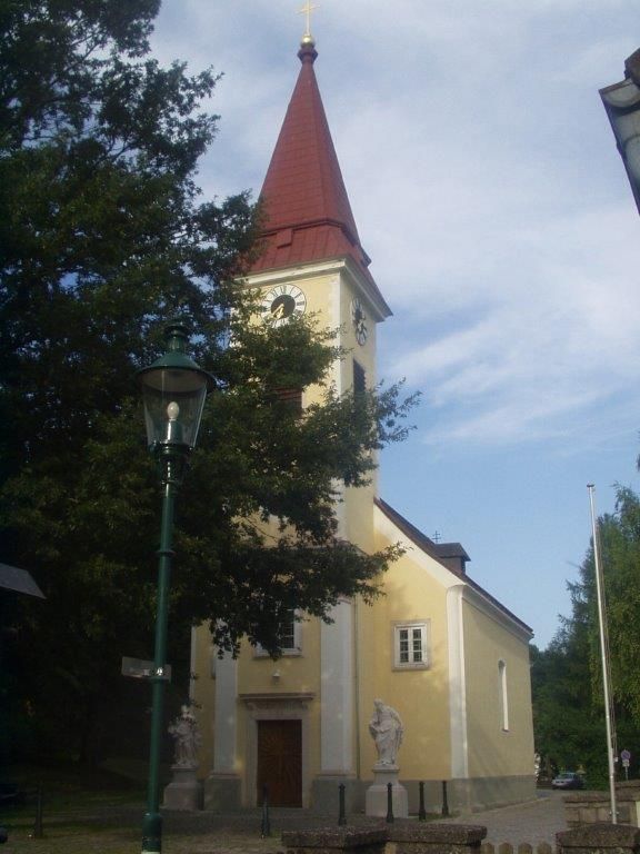 Exteriérový pohľad na farský kostol Sulz s vežou a hodinami.