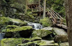 Umgeben von majestätischen Bäumen und sanften Felsen fließt das Wasser des Lohnbachfalls in glitzernden Strahlen über die moosbedeckten Steine. Die frische, klare Luft und das sanfte Plätschern des Wassers schaffen eine friedliche Atmosphäre, die zum Verweilen einlädt.