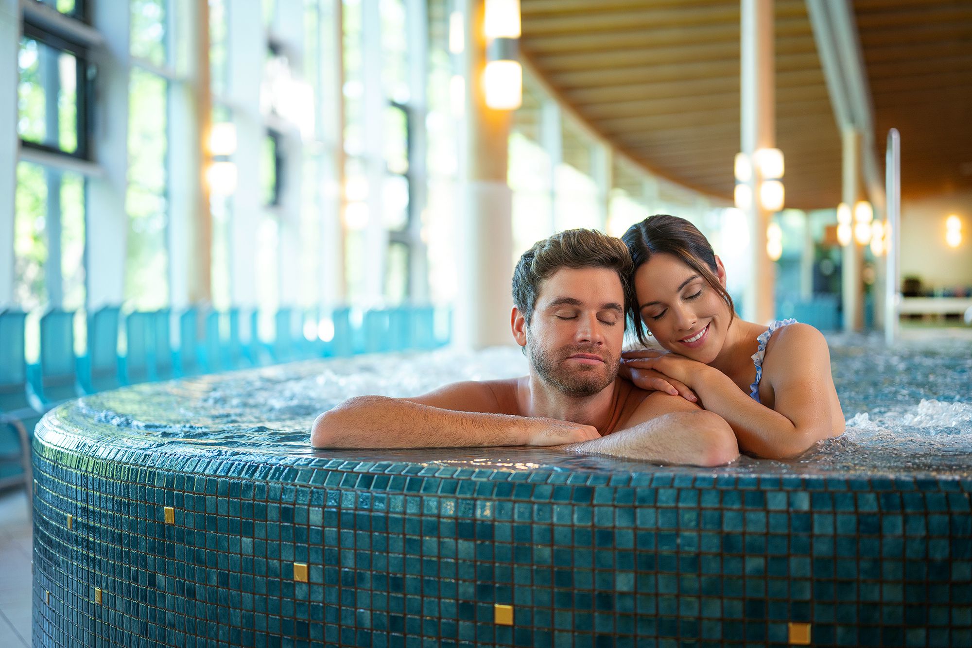 Pár relaxuje vo vírivke v modernom wellness centre s veľkými oknami.
