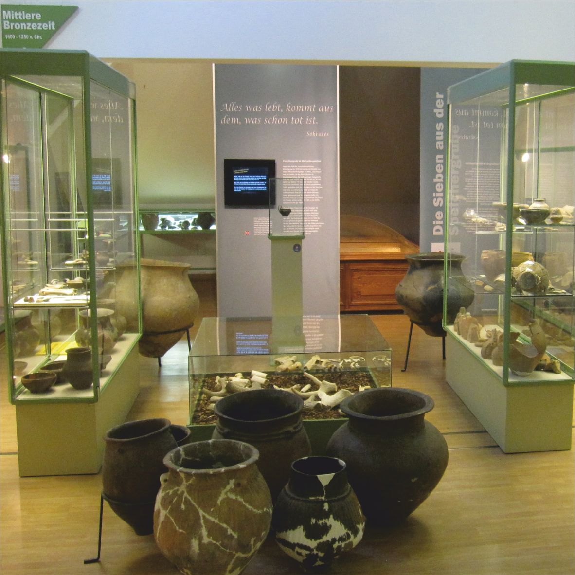 Múzejná expozícia so starožitnými hlinenými nádobami a vitrínami.