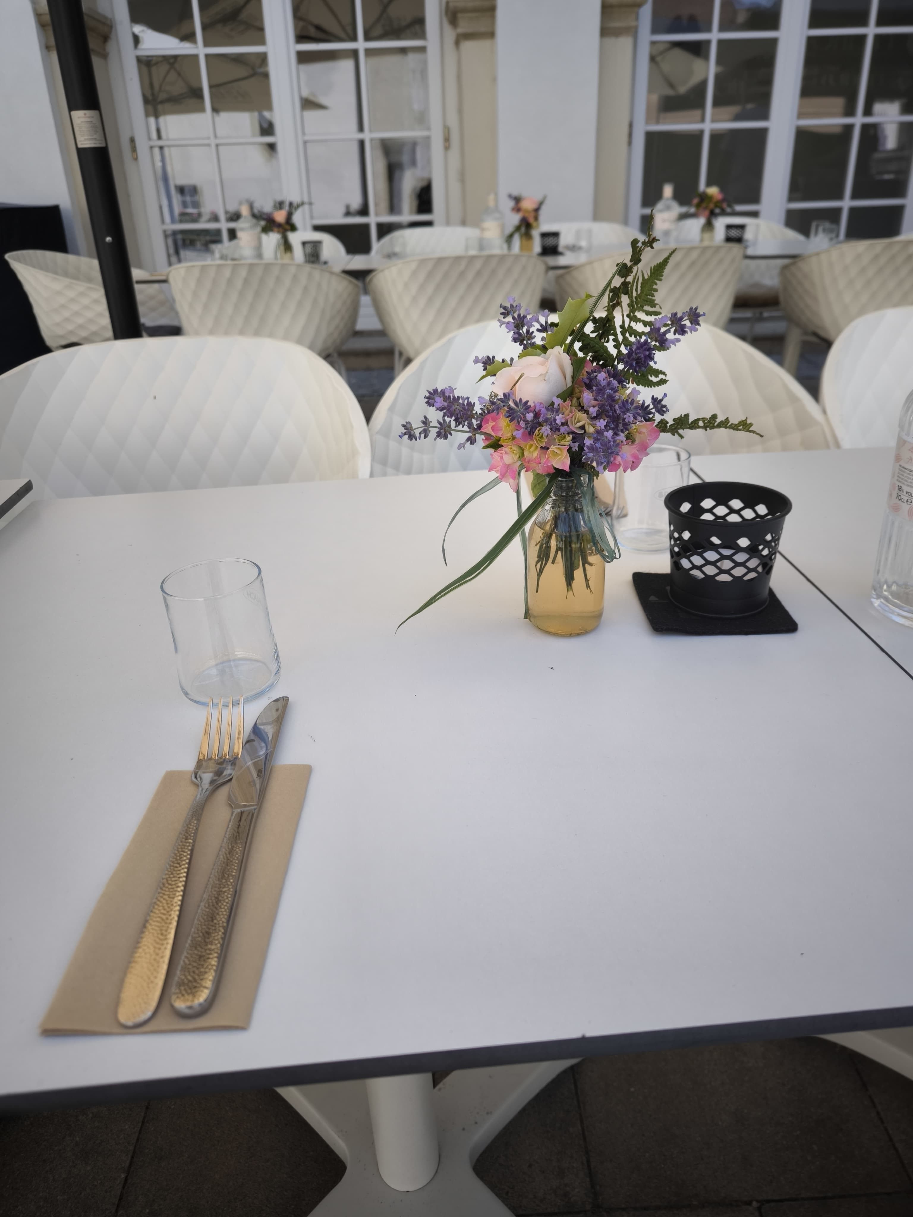 Stolovanie na terase s kyticou kvetov a príbormi.