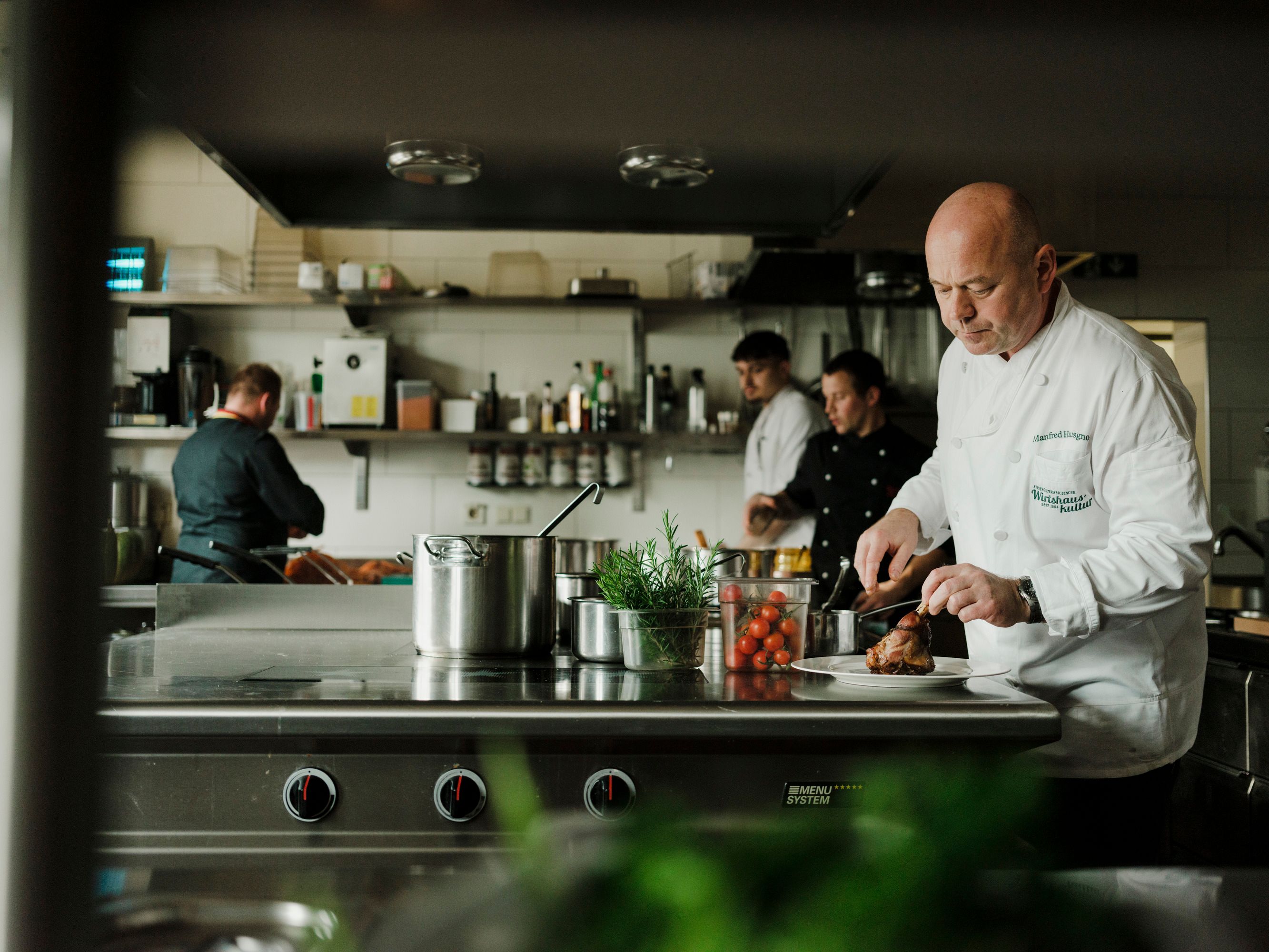 Kuchári pracujú v profesionálnej kuchyni, jeden krája mäso.