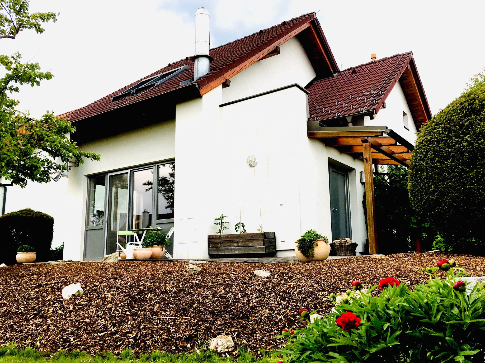 Pohľad zvonku na moderný rodinný dom so záhradou a terasou.