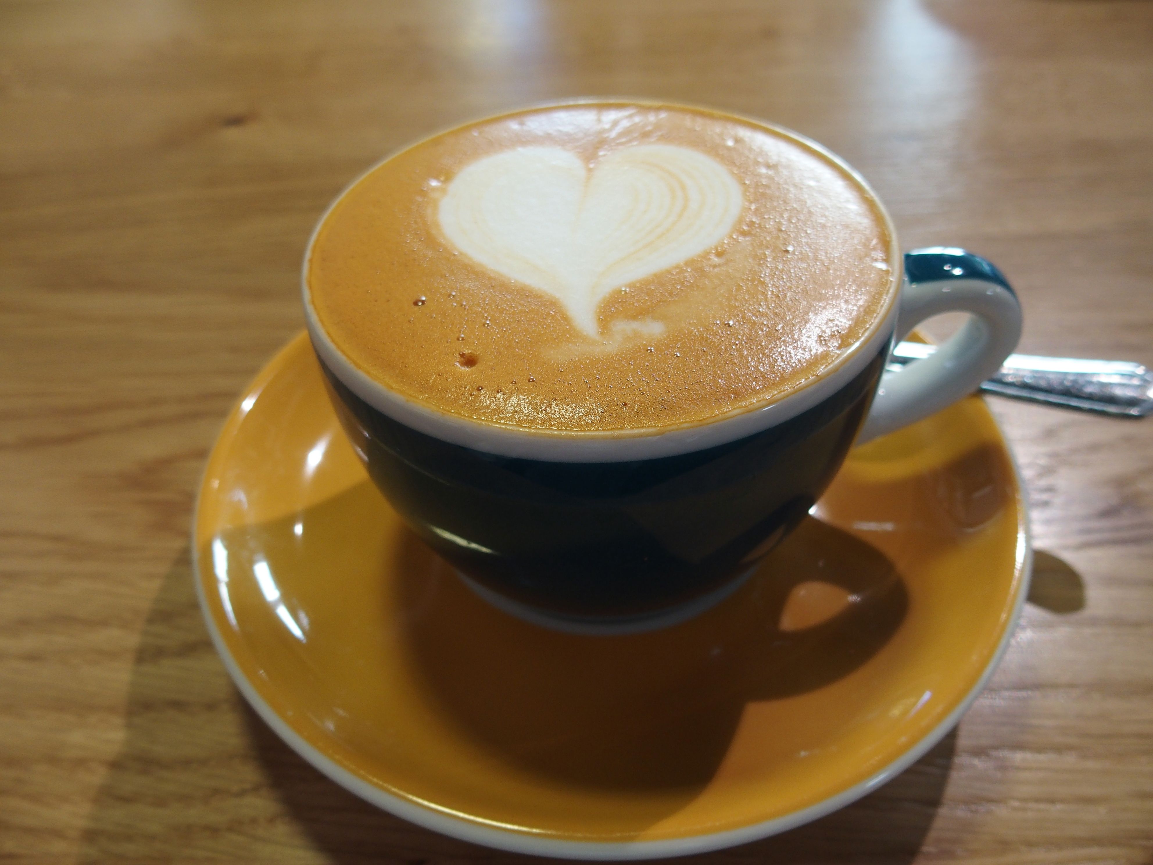 Šálka cappuccina s latte v tvare srdca na drevenom stole.