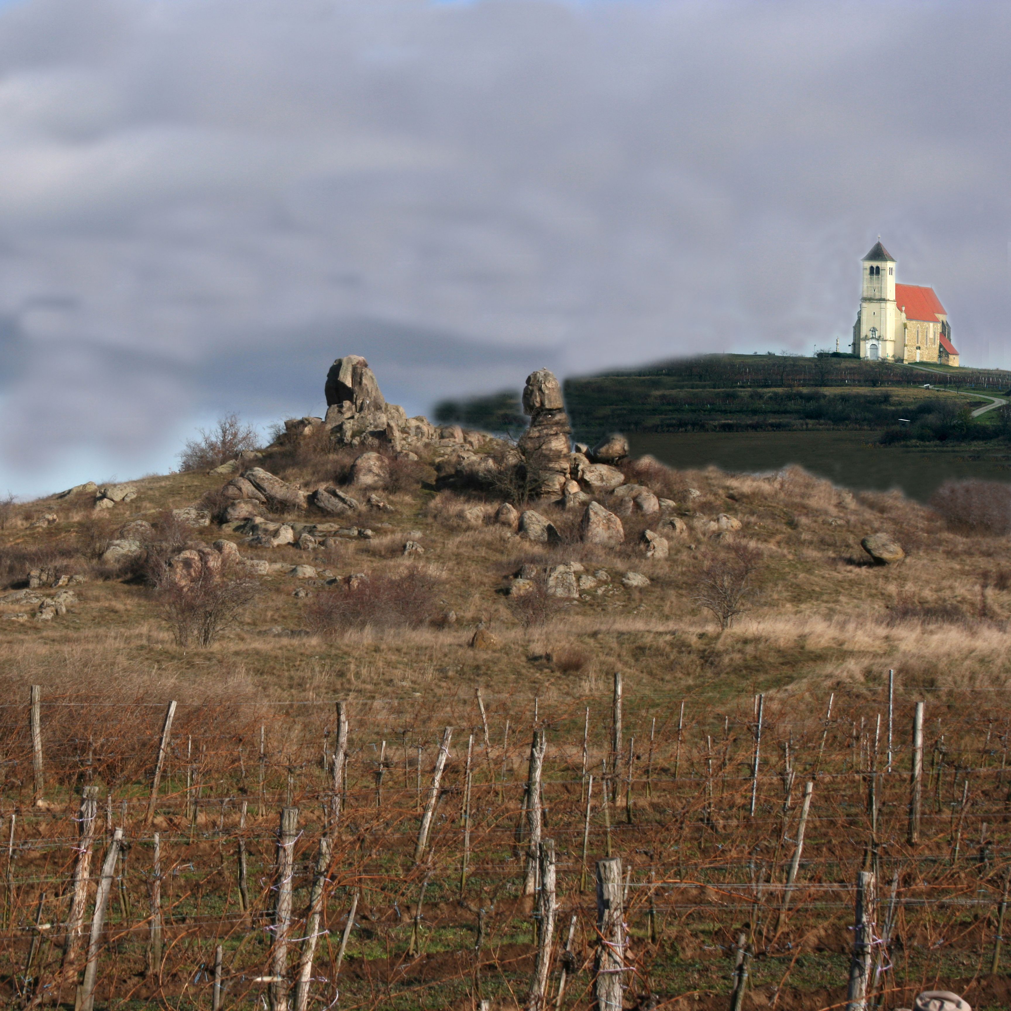 Krajina so skalnými útvarmi a kostolom v pozadí.