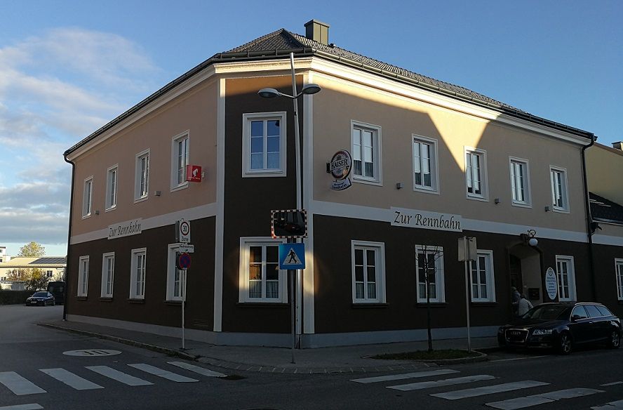 Nárožná budova s nápisom "Zur Rennbahn" a nápisom Kaiser beer.