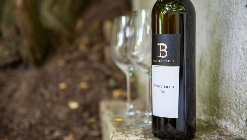 Fľaša vína s dvoma prázdnymi pohármi vonku.