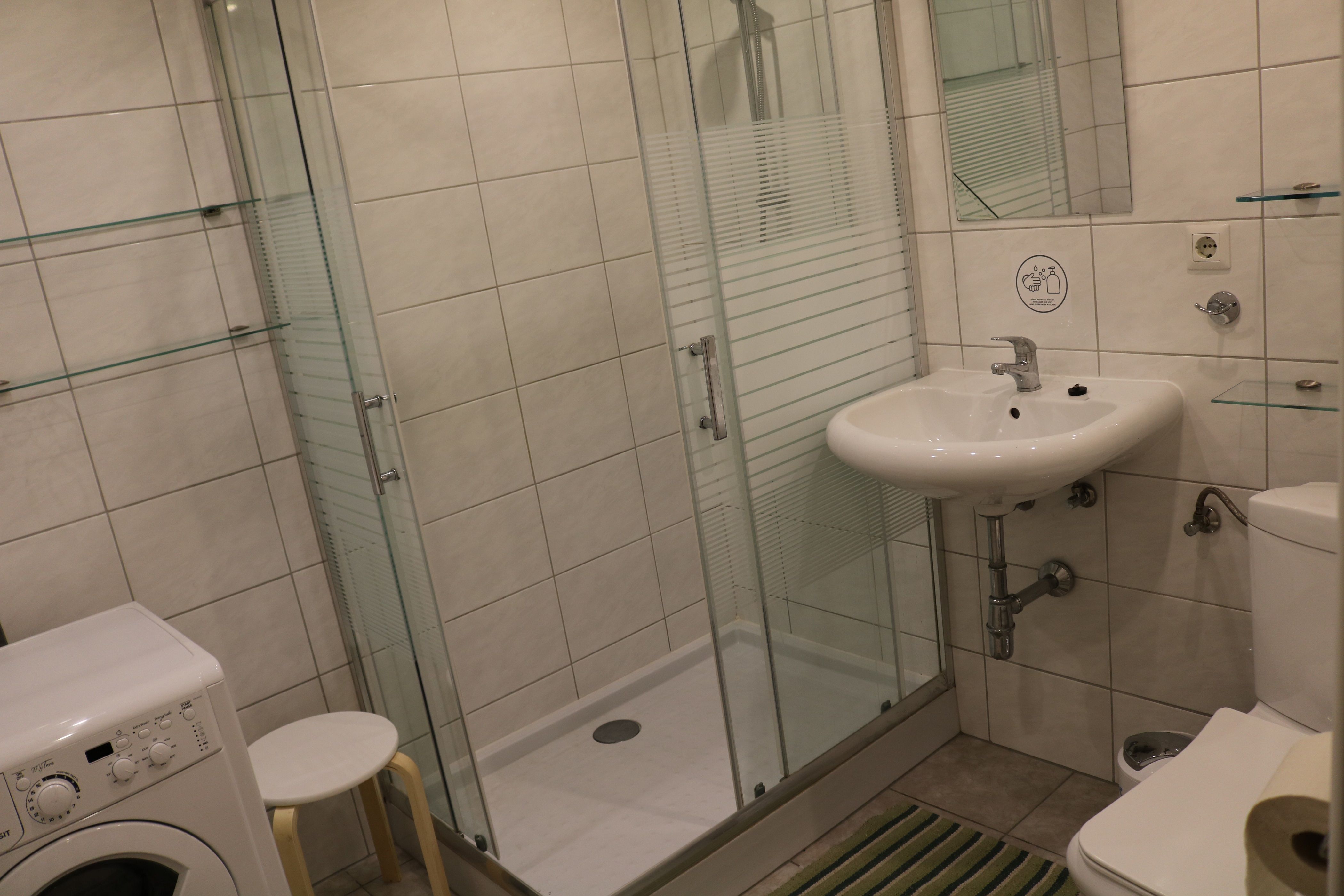 Moderná kúpeľňa so sprchovacím kútom, umývadlom, WC a práčkou.