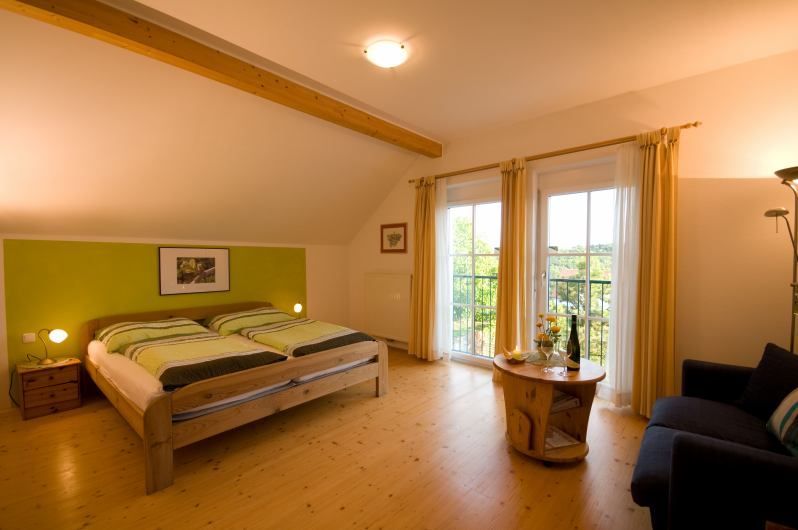 Útulná spálňa s manželskou posteľou, dreveným nábytkom a prístupom na balkón.