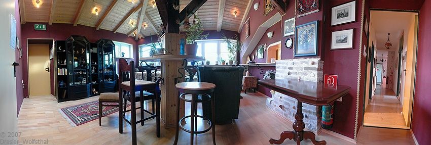 Útulná klubová miestnosť s dreveným nábytkom, kobercom a obrazmi na stenách.