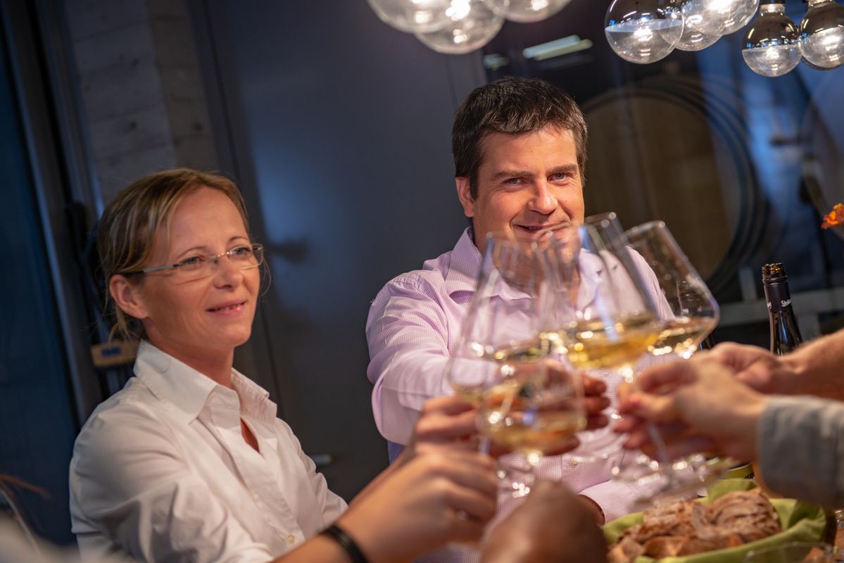 Ľudia si pri stole cinknú pohárom vína.