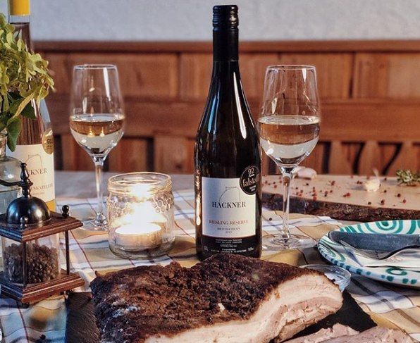 Stôl s fľašou vína, dvoma pohármi, sviečkou a miskou na mäso.