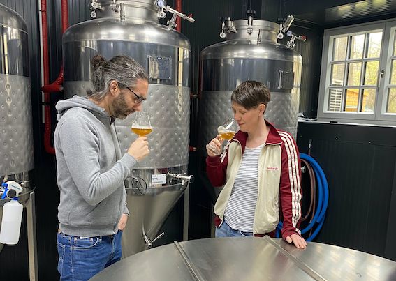 Pohľad do interi&eacute;ru modernej kaviarne s dreven&yacute;mi tr&aacute;mami, barov&yacute;m pultom a stolmi.